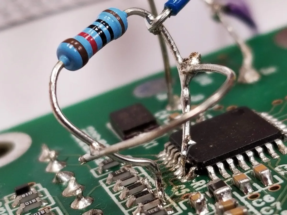 Macro close-up of a resistor bodge wire soldered across ATmega IC pins